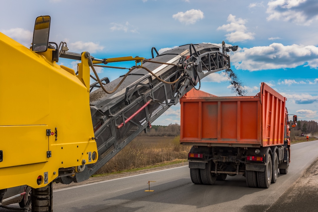 Milling equipment removing old asphalt on a commercial roadway