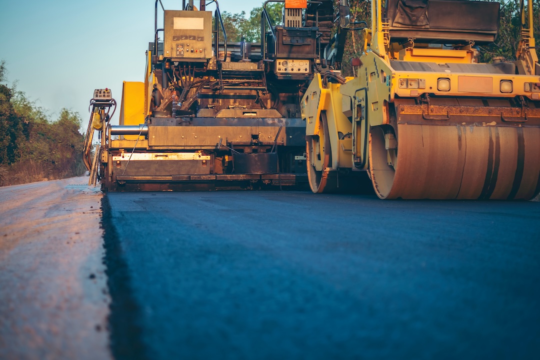 Paver and roller compacting a commercial parking lot surface